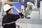 Female engineer wearing protective mask and glove to protect against Covid-19 and looking at robot CNC machine in smart factor