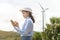 Female engineer working on the seaside wearing a protective helmet over electrical turbines background