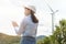 Female engineer working on the seaside wearing a protective helmet over electrical turbines background