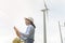 Female engineer working on the seaside wearing a protective helmet over electrical turbines background