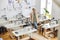 Female entrepreneur with tape measure leans onto table in empty sewing workshop