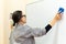 A female entrepreneur or teacher writing on a blackboard with an erasable presentation marker in a conference room