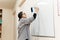 A female entrepreneur or teacher writing on a blackboard with an erasable presentation marker in a conference room