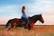 Female equestrian riding bay horse in a field