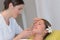 Female esthetician massaging head and face young woman