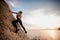 Female extreme climber conquers steep rock against the sunset over river.