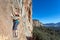 Female extreme Climber hanging on high vertical Rock