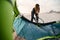 Female Extreme Sports Kite Surfer Prepping Kite On Beach At Sunset