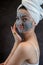 Female face with cosmetics cleansing gray bubble mask on dblack background