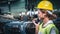 Female factory worker using handheld radio receiver for communication.