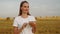 Female farmer stands in a wheat field at sunset and works with a digital tablet. Smart farming and precision farming