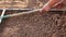 Female farmer using a rake to level the brown soil in the garden