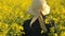 Female Farmer Walking in Oilseed Rapeseed Cultivated Agricultural Field Examining and Controlling The Growth of Plants