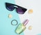 Female fashion accessories on a blue white pastel background. Sunglasses, perfume bottle, shells. Summer beach accessories.