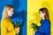 Female fashion models holding chrysanthemum bouquets and looking at each other on blue