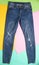 Female fashionable ragged faded jeans on a colored pastel background. Minimalism, top view.