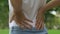 Female feels acute back pain while walking outdoors, inflammation of kidneys