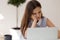 Female feels boredom seated at desk looking at laptop screen