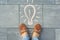 Female feet with abstract image drawing of light bulb written on grey sidewalk