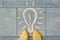 Female feet with abstract image drawing of light bulb written on grey sidewalk