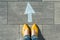 Female feet with arrow painted on the asphalt.