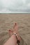 Female feet on the beach. Shell bracelet.