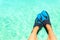 Female feet with blue snorkeler fins over turquoise blue water