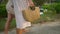 Female feet in dresses going barefoot to tropical beach along path. Two young women walking, holding straw bag on exotic