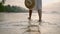 Female feet going barefoot in sea surf water edge at sunset. Splashing foamy water. Young woman's legs walk slowly