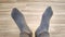 Female feet in gray worn socks move fingers on floor. Holey sock. Movement to beat of music, good mood. Close-up. Shooting on