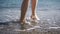 Female feet of hiker tourist walking barefoot on shore at sunset.