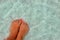 Female feet with manicure on stone, covered with salt formations between the waves in the water. Crystallization of salt on stone