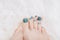 Female feet with marine nail design. Glitter cyan nail polish pedicure on white fluffy background