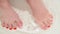 Female feet with red lacquer on nails in bathtub with water