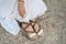 Female feet in sandals on sandy Greek shore. Girl resting on beach