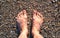 Female feet on the sea sand from seashells, top view.