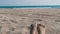 Female feet sunbathing on beach against the background of sand and blue sea with waves. Womans bare feet on a beach