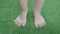 Female feet is touching artificial lawn grass.