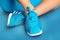 Female feet in turquoise sneakers on turquoise sports mat