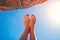 Female feet under beach umbrella. Woman relaxing by sea. Summer vacation