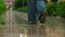 Female feet walking on the street on puddles. Woman steps by the wet road through the city under the rain. Rainy summer