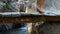 Female feet walking on wooden bridge across stony river in mountains. Close up barefoot woman walking along suspension