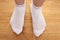 Female feet in white socks on a wooden floor, close-up, copy space