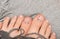 Female feets with rose nail polish. Woman legs with rose nail design on fabric background
