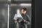 Female financial analyst holding papers studying documents standing in the elevator. Ambitious businessman is reading carefully