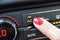 Female finger on the button to activate the air conditioning in the car