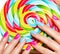 Female fingers with colorful nails on the background of vivid multicolor sweet candy