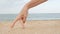 Female fingers walk on the sand against the background of the sea imitating a man`s gait, hand make step, playing on the beach, fu