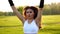 Female fitness instructor doing jumping jacks exercising in green park