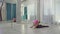 The female fitness trainer does flexibility exersices on the wooden floor in the bright gym